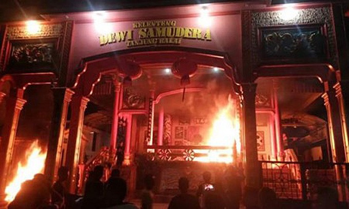 In riot – Residents gather in front of Dewi Samudera, a Chinese temple or pagoda in Tanjung Balai, North Sumatra, which was plundered and set ablaze by angry mobs on Friday evening.  