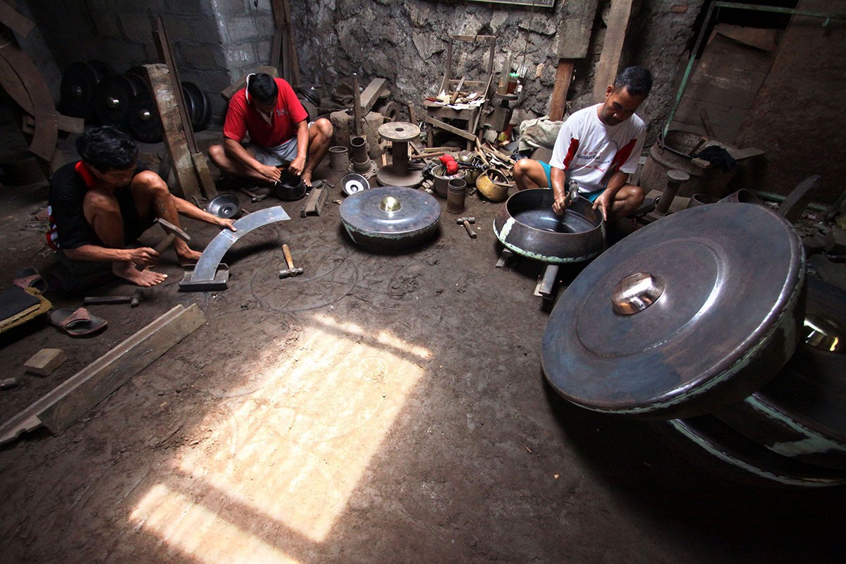 Three men cut and forge metal plates in the Daliyono Legiono workshop. Image: JP/Aditya Sagita