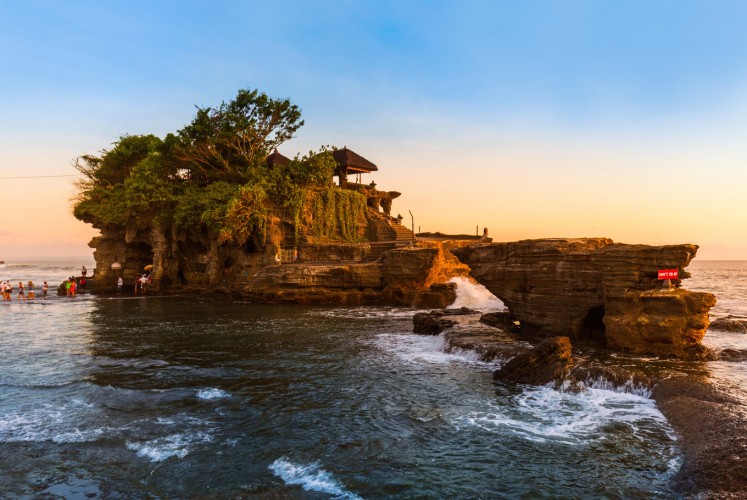 Tidal foam washes up against the natural rock base of Tanah Lot Temple.