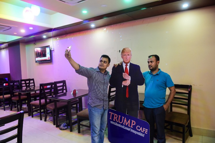 In this photograph taken on July 13, 2017, a Bangladeshi customer takes selfie with a cutout US President Donald Trump at the Trump Cafe in Dhaka. 