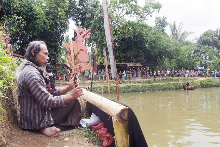 Storyteller: Artist Agus Bimo Prayitno, 58, performs Jantur, a narration using shadow puppets, on the bank of Kedung Bunder.