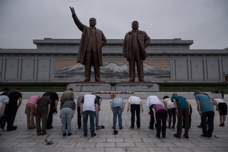 A group of tourists bow before statues of late North Korean leaders Kim Il-Sung (L) and Kim Jong-Il (R), on Mansu hill in Pyongyang on July 23, 2017. 