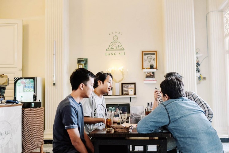 Reconnecting: Four customers of the younger generation chat at the Kedai Bang Ali coffee shop. The coffee shop envisions reconnecting Jakarta's citizens with the former governor's vision and character through what and how it serves its guests.