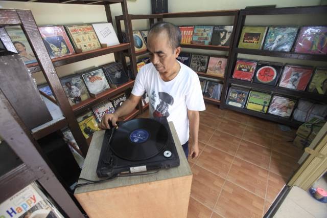 Old guard: Owner of Lian Store, Lian Nasutian plays an old Indonesian record for customers inside his roadside music shop on Jl. Surabaya, Menteng, Central Jakarta.