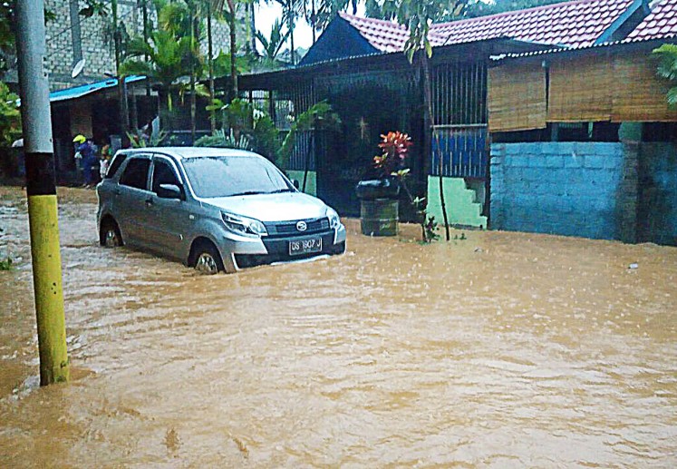 A car is stuck in floodwater at the Organda residential complex in Padangbulan, Jayapura, Papua, on Thursday. Jayapura is one of the cities to get the Adipura Award from the Forestry and Environment Ministry this year. The award is given to cities and regencies for achievements in cleanliness, healthiness and sustainable development.