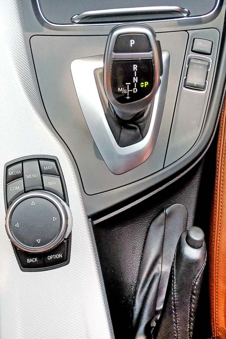 Gears: The iDrive Touch Controller (bottom left), automatic 8-speed Steptronic Sport transmission stick (center), comfort and eco pro driving mode button (top right) and the manual handbrake (bottom right).