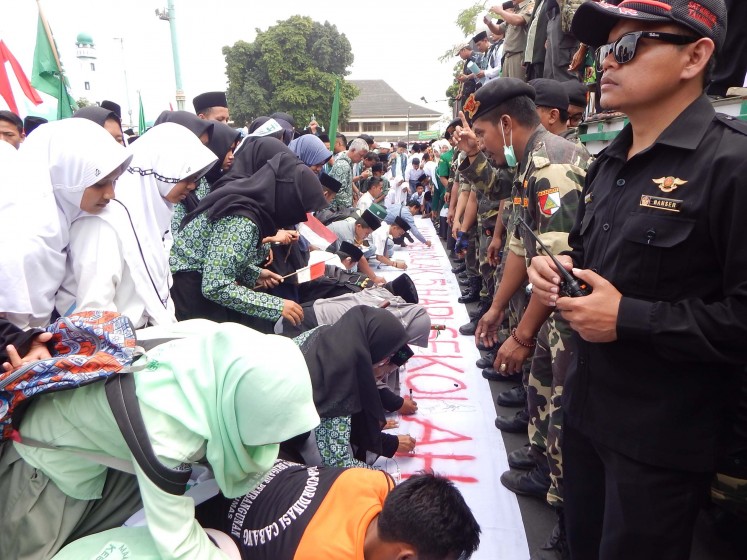 Thousands of Nahdlatul Ulama members and Islamic school students sign a large white banner during a rally at Purwokerto town square in Banyumas, Central Java, on Monday. They demanded the annulment of the controversial five-day school policy issued by Culture and Education Minister Muhadjir Effendy.   