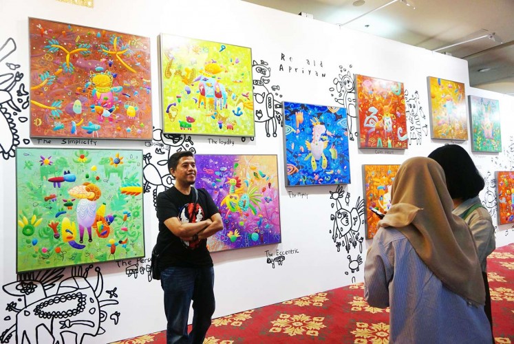 Youthful force: A visitor poses with Ronald Apriyam's paintings at Art Jakarta 2017 at Pacific Place in Jakarta. The arts fair, previously known as Bazaar Art, showcased a wide range of works by young artists and positioned itself as the people's arts fair. 