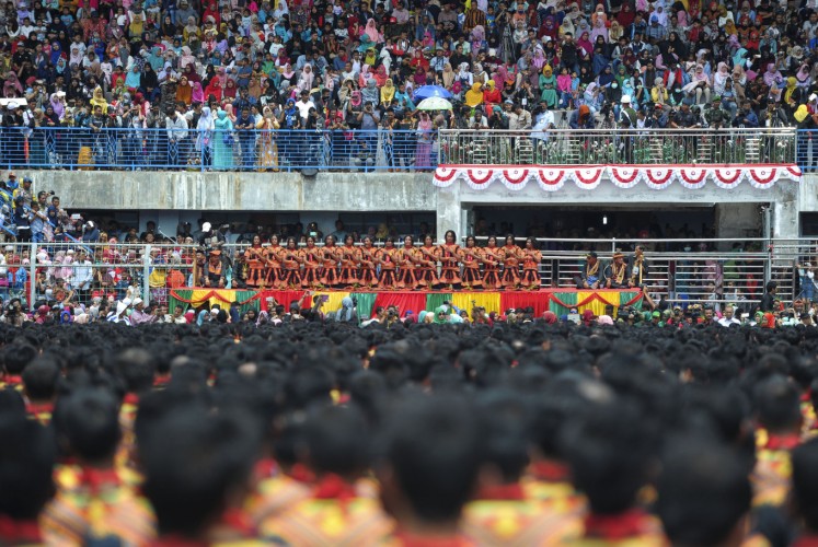 Residents (top) watch participants take part in a mass traditional Saman dance performance in the Gayo Lues highland district in Aceh on Indonesia's Sumatra island on August 13, 2017. More than 10,000 people turned out in Indonesia's Aceh on August 13 to stage a record-breaking song and dance performance stressing the need to conserve a threatened national park in the westernmost province.