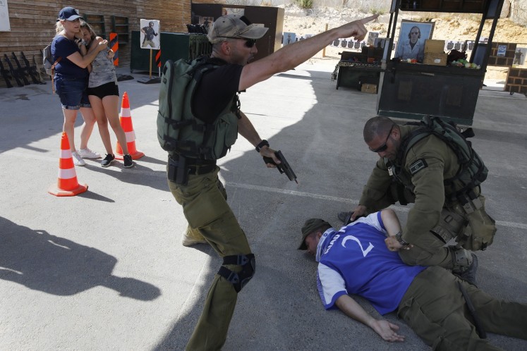 Foreign tourists (L) react as Israeli intructors neutralize a man during a simulation of a knife attack at a market.