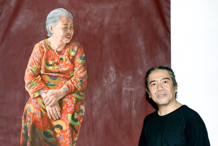 The artist: Sudigdo poses in front of his painting, A Golden Smile.