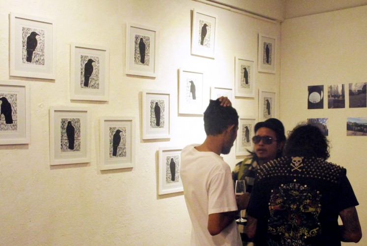 Visitors converse in front of the 'Black Bird' series of linocut on paper.