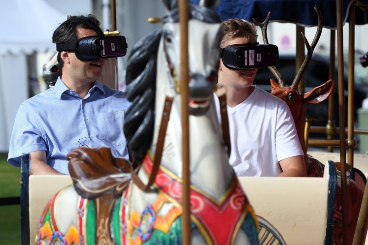 Visitors sitting on a carousel try out virtual glasses at the booth of Deutsche Telekom at the IFA Consumer Electronics Fair in Berlin on September 2, 2017. 