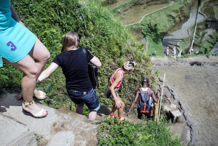 Step by step: Foreign tourists climb down the paddy terrace wall in Ceking.