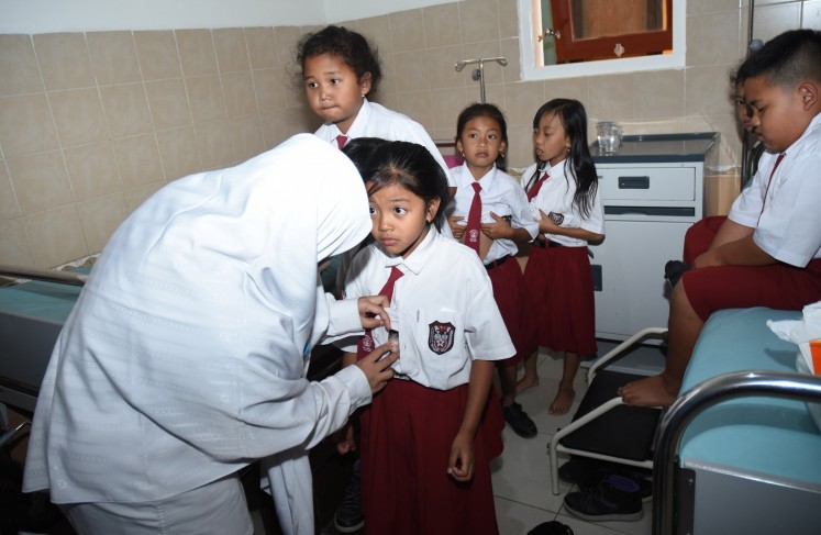 Take a deep breath: A health worker checks the condition of a student from state elementary school SDN Pandanrejo in Batu city, East Java, at community health center Puskesmas Bumiaji, on Sept.6. 