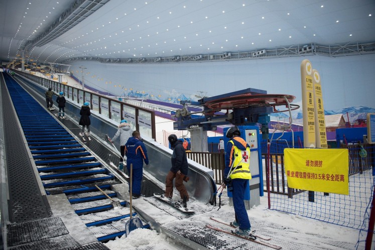 In this picture taken on August 22, 2017, people use a snow escalator at the Wanda Harbin Ice and Snow Park in Harbin. At Dalian Wanda Group's new Ice and Snow Park, chilly winds blew snowflakes around skiers zipping down the manmade slopes of the world's largest indoor ski park, a potent symbol of China's ambitions to turn itself into a winter sports powerhouse ahead of the 2022 Winter Olympics in Beijing.