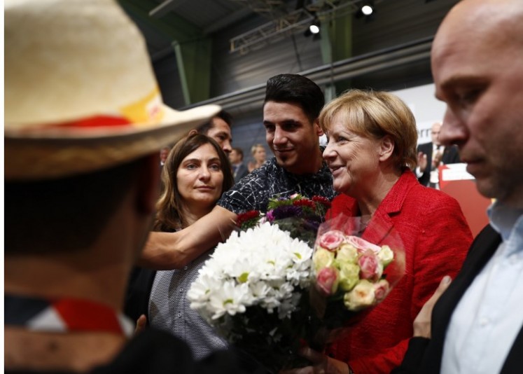 Syrian refugees offer flowers to German Chancellor and Christian Democratic Union's (CDU) main candidate Angela Merkel (right) after she gave a speech during an election rally in Schwerin, northern Germany, on Sept. 19, 2017. Germany goes to the polls for parliamentary elections on Sept. 24, 2017.