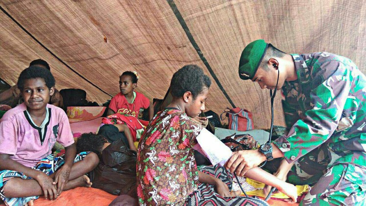 Challenging task: A member of the army provides health care to local residents in a village in Papua. Poor access to healthcare services in Papua's remote areas remains unresolved. 