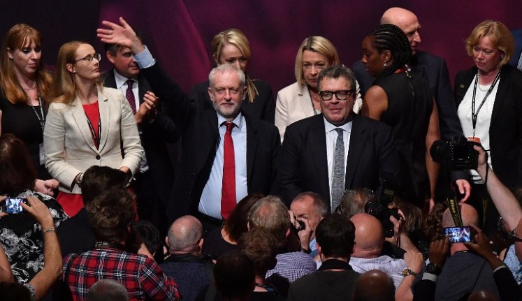 Britain's opposition Labour party Leader Jeremy Corbyn (left) waves as he stands with members of his shadow cabinet after Britain's opposition Labour party's Deputy Leader Tom Watson (right) delivered a speech on the third day of the Labour Party conference in Brighton, southern England, on Sept. 26, 2017. 