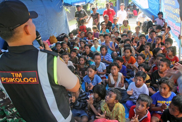 Listen up, kids: A policeman speaks with children at the Swecapura sports complex, which has become one of the centers for evacuees fleeing from the rumbling Mount Agung in Bali.