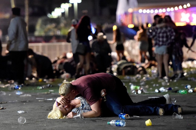 A man lays on top of a woman as others flee the Route 91 Harvest country music festival grounds after gunman opened fire on festival-goers