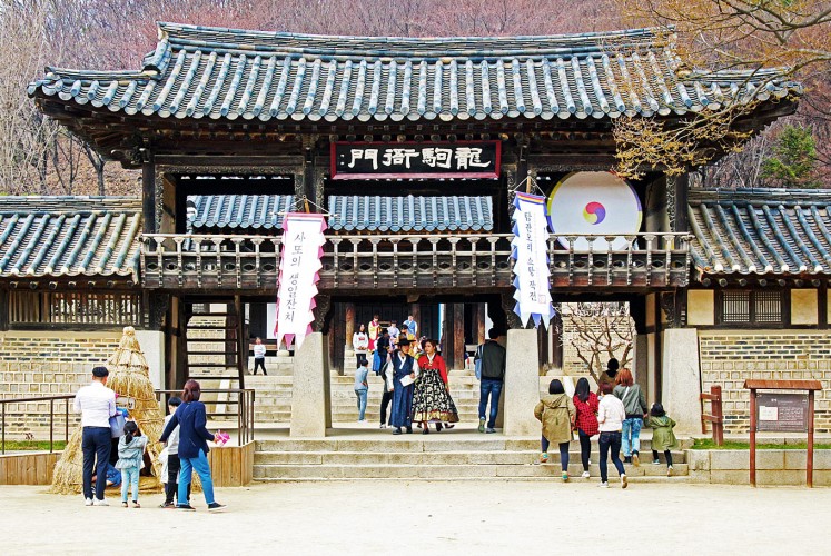 Walk into the past: A couple in traditional Korean outfits walk through an ancient entrance gate.