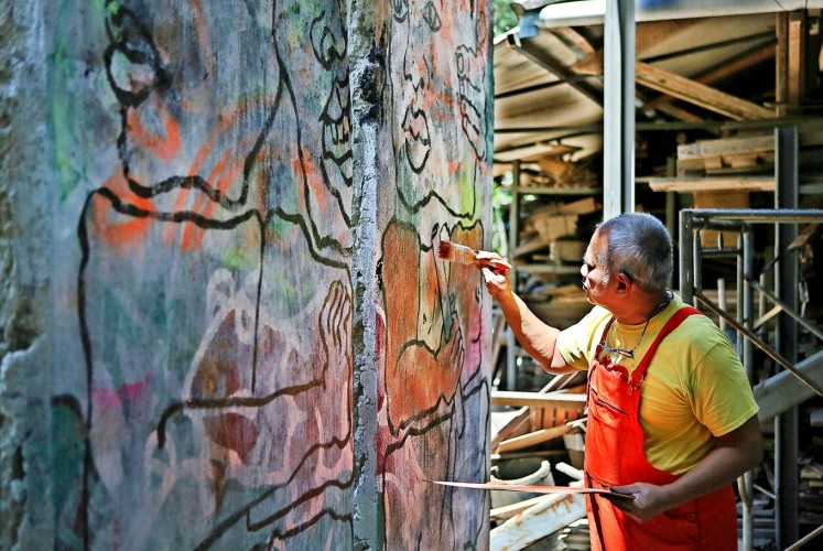 In progress: Artist Teguh Onsterik paints on a segment on the historic Berlin Wall at his workshop in Depok, West Java, on Aug. 2.