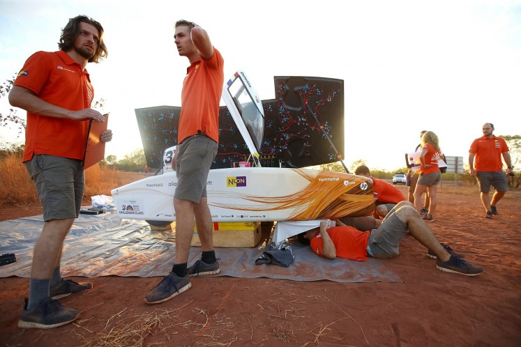Team members of Nuon Solar Team from the Netherlands preparing their vehicle 'Nuna9' to catch the first morning sun near Dunmarra on the second day of racing. 