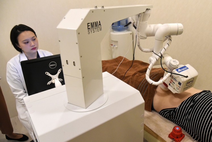 Singaporean physician Calista Lim Hui Min (L) monitors progress as Emma massages Elaine Low.