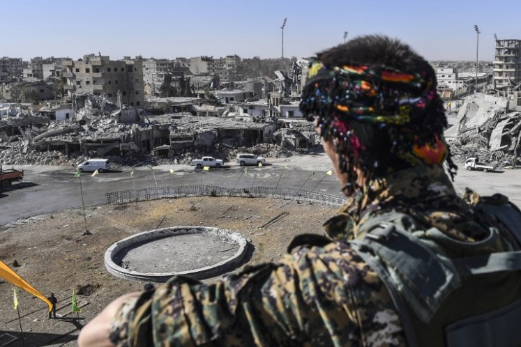 A member of the Syrian Democratic Forces (SDF) stands at a position overlooking the iconic Al-Naim square in Raqa on Oct. 18, 2017. The SDF fighters flushed jihadist holdouts from Raqa's main hospital and municipal stadium, wrapping up a more than four-month offensive against what used to be the inner sanctum of IS's self-proclaimed 