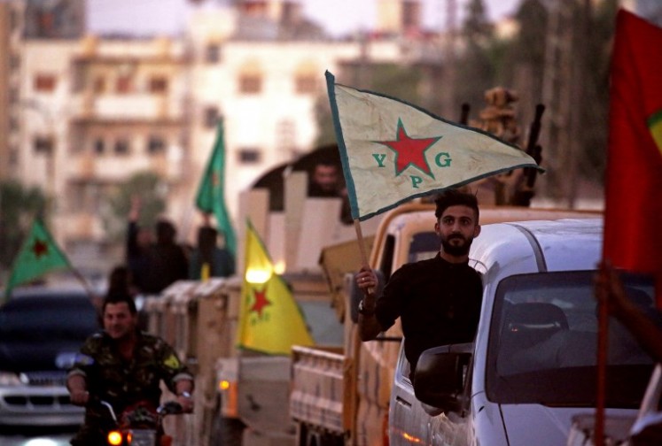 Supporters and fighters of the Syrian Kurdish People's Protection Units (YPG) drive in the street in Qamishli waving flags as they celebrate after the Syrian Democratic Forces (SDF) announced they had taken full control of Raqa from the Islamic State (IS) group on Oct. 17, 2017. The SDF is made up of Kurds, Arab Muslims and Christians who have joined forces to battle IS.