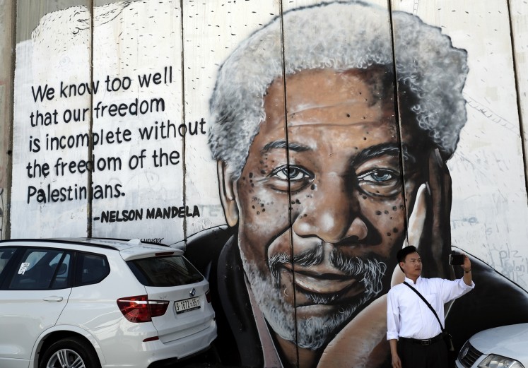A man takes a selfie in front of a new piece of graffiti depicting US actor Morgan Freeman who played the role of former African president Nelson Mandela in the film 'Invictus'.