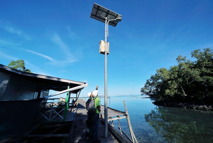 Green energy: Two workers check a street lamp that uses solar power on Teluk Harapan.