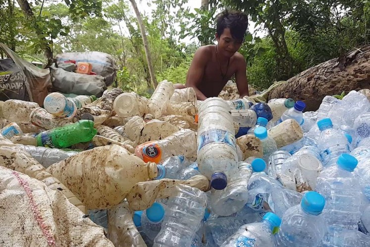 A resident near the Puuwatu landfill site sorts plastic bottles for recycling. 