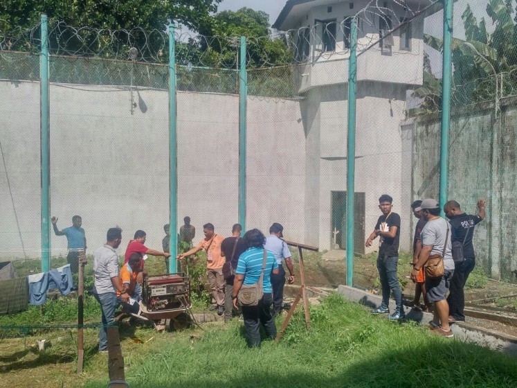 Scene of the crime: Jayapura Police officers on Wednesday examine security wire fences destroyed by the five escapees.