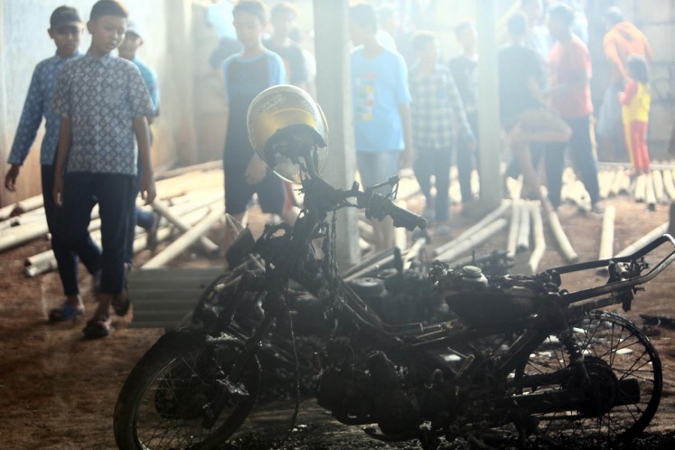 Residents look at the burnt motorcycle in the vicinity of the decimated fireworks factory in Kosambi, Tangerang on Thursday. 