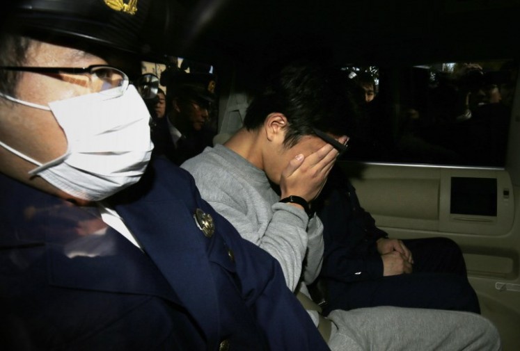 Suspect Takahiro Shiraishi (center) covers his face with his hands as he is transported to the prosecutor's office from a police station in Tokyo on Nov. 1, 2017. The 27-year-old Japanese man, who was arrested after police found nine dismembered corpses rotting in his house, has confessed to killing all his victims over a two-month spree after contacting them via Twitter, media reports.
