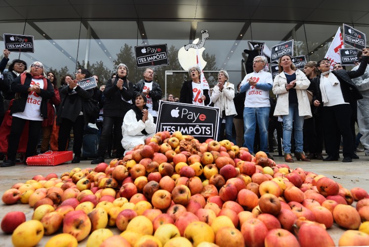 Activists of the Association for the Taxation of financial Transactions and Citizen's Action (ATTAC) stand next to apples and signs reading 