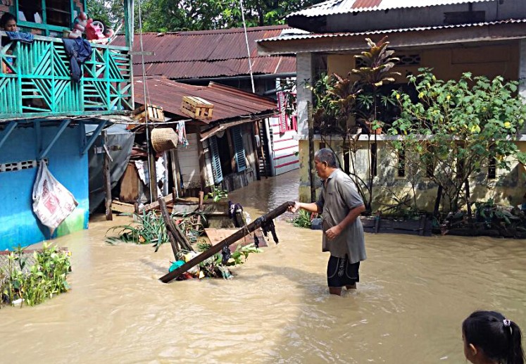 A man lifts up a large piece of debris that was swept by floodwater in Aur subdistrict, Medan Maimon, Medan, North Sumatra, on Tuesday.
