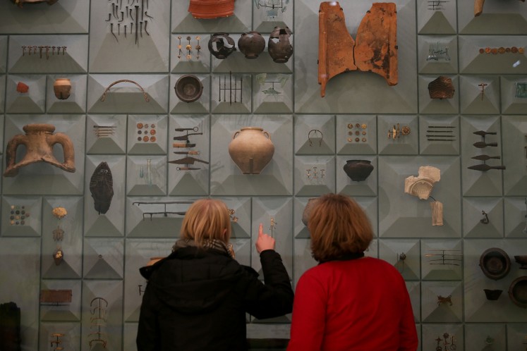 Visitors stand in front of Roman-era items during a press preview at the London Mithraeum.