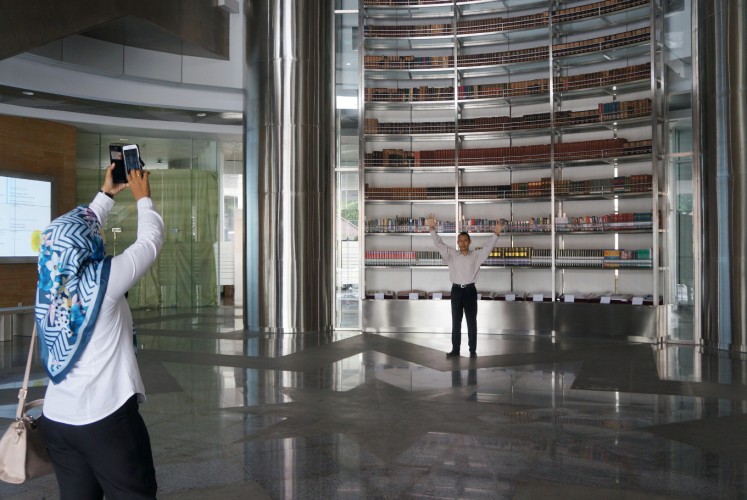 A visitor takes a photo of the giant bookshelf in the lobby of the National Library of Indonesia. 