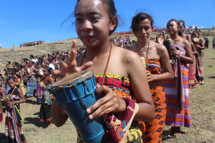 A young female dancer hits a tihar, a small traditional drum, during the Likurai dance. JP/Djemi Amnifu