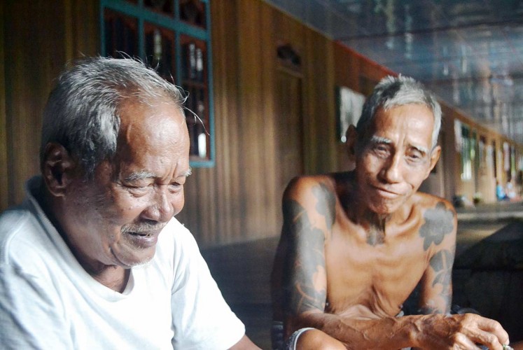 Elders: The tuai adat (customary chief) of Meliau, Apai Inyang (left), talks with local resident Apai Ubit in a traditional house corridor called a ruai.