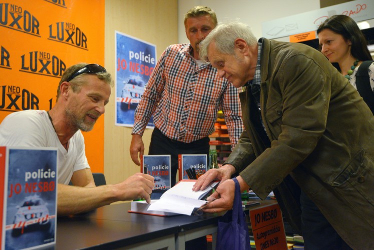 Norwegian author Jo Nesbo (L) signs a copy of the Czech edition of his novel 'Police' ('Policie') at Luxor bookshop in Prague, Czech Republic, on May 04, 2015.