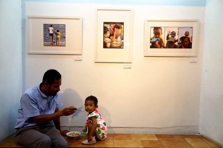 A father poses with his daughter while they are roaming around the venue of 'Ini Ayah Hebatku' photo exhibition on Monday, Nov. 20 at Bentara Budaya, Central Jakarta. 
