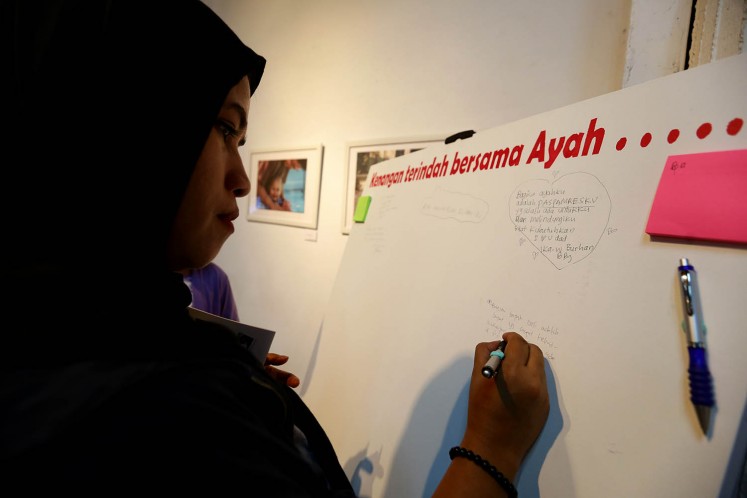 A visitor writes about her most memorable moment with her father on a canvas at 'Ini Ayah Hebatku' photo exhibition on Monday, Nov. 20 at Bentara Budaya, Central Jakarta.