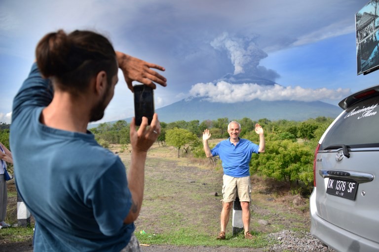 A foreign tourist takes pictures in front of Mount Agung erupting seen from Kubu sub-district in Karangasem Regency, on Indonesia's resort island of Bali on Nov. 27, 2017. Image: Agence France -Presse/Sonny Tumbelaka 