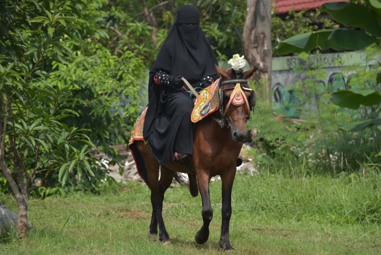 This picture taken on November 12, 2017 shows an Indonesian Muslim woman riding a horse in Bekasi. Riding a horse or nailing an archery target is tough at the best of times -- it's even harder when you're wearing a niqab. But that isn't about to stop a group of Indonesian women who have banded together as they face prejudice against the face-covering veil at the centre of a heated global debate over religious freedom and women's rights.