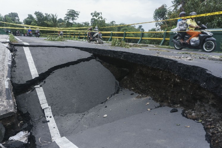 Locals pass through a collapsed bridge on motorcycles in Imogiri, Bantul regency, Yogyakarta, on Thursday. 
