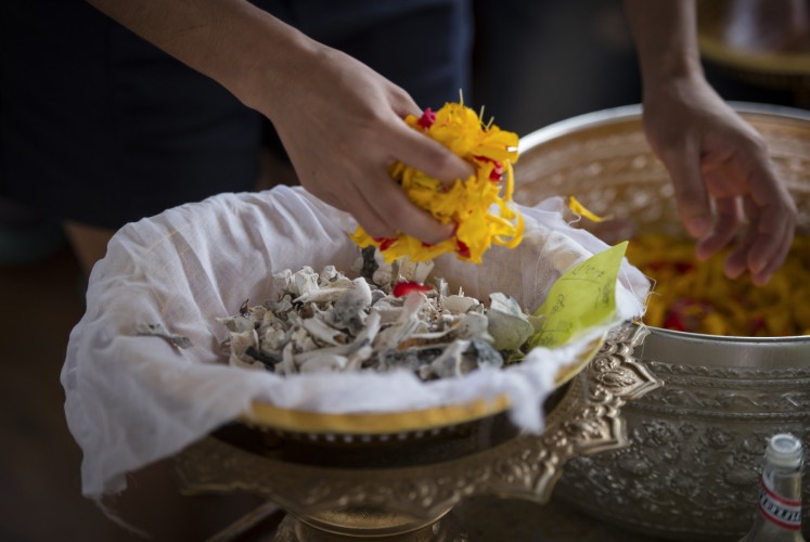 This photo taken on November 5, 2017 shows the bones and ashes of a pet dog being covered in flowers, before being released in the Chaopraya river in Bangkok. Pet cremations, complete with Buddhist rituals, are popping up across Bangkok for dogs, cats and even monkeys. In a devout Buddhist kingdom where religion and superstitious beliefs entwine, some pet owners believe the monk-led send off will boost their pets' chances of being reincarnated as a higher being.
